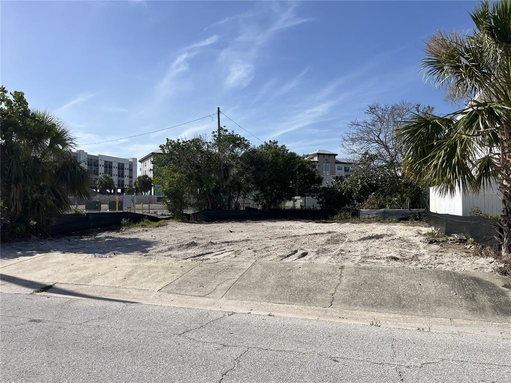 A vacant, sandy residential lot is bordered by a sidewalk, palm trees, and black fencing — 180 E MADEIRA AVENUE, MADEIRA BEACH, FL