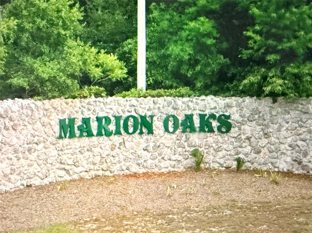 A stone wall features the green text "MARION OAKS" in front of a wooded area — 0000 MARION OAKS BOULEVARD, OCALA, FL