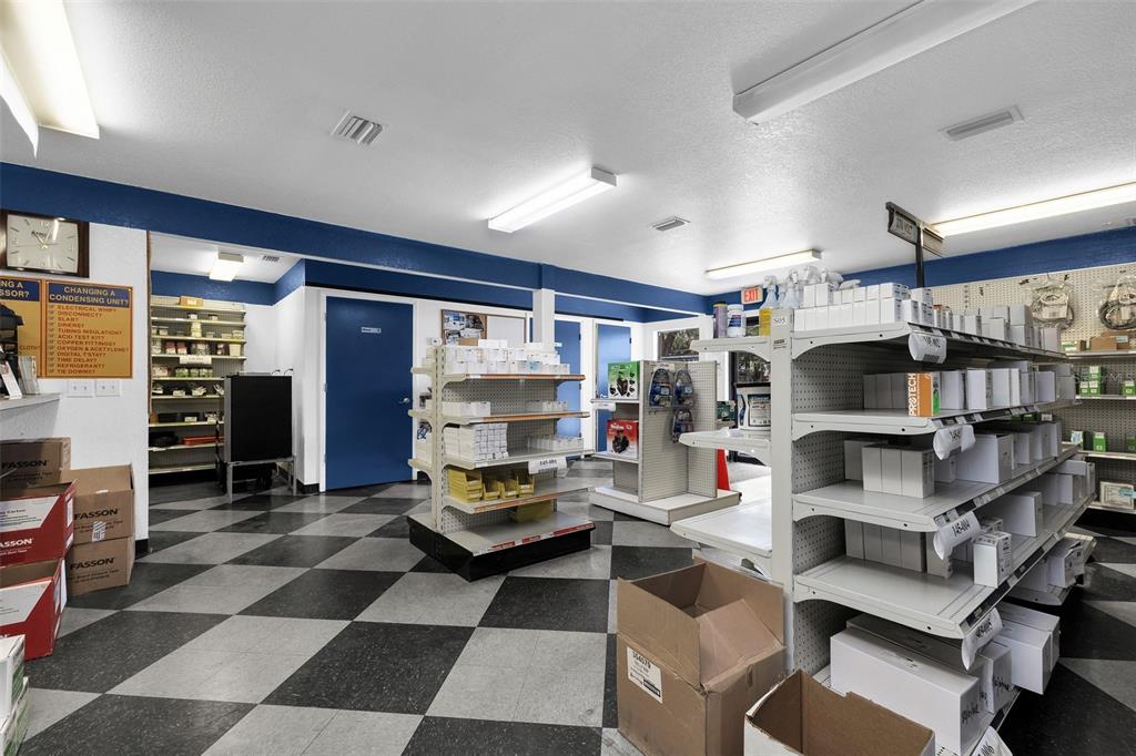A retail store interior features checkered flooring, white shelving units, and blue accent walls — 18230 PAULSON DRIVE, PORT CHARLOTTE, FL