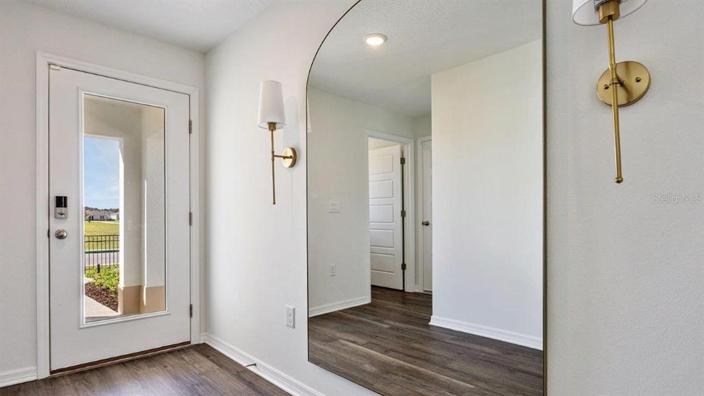 An entryway features a white front door, a large arched mirror, and gold wall sconces — 7840 FORREST FOX WAY, LAKELAND, FL