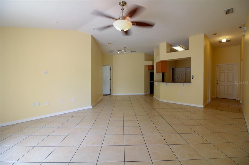 An open-concept living area features light yellow walls, tile flooring, and a ceiling fan — 1702 HOLTON ROAD, LAKELAND, FL