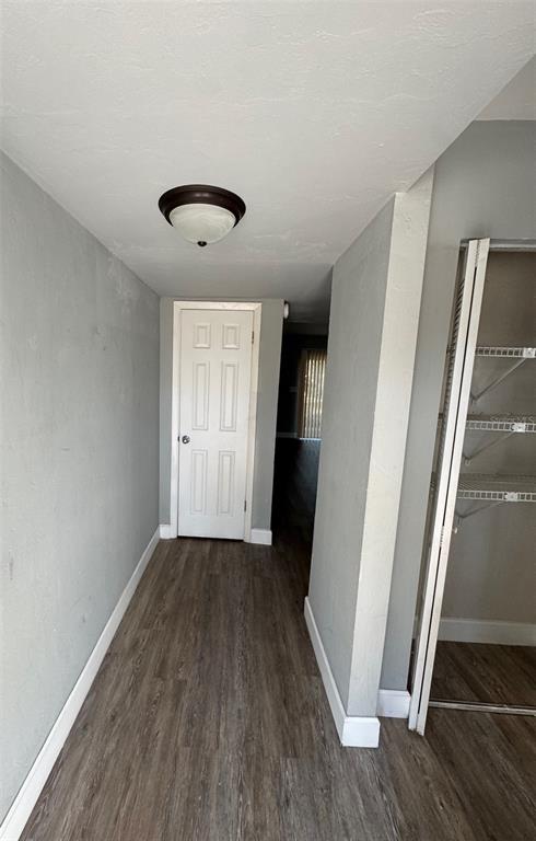 A hallway with wood-look flooring leads to a closed white door and an open closet — 7130 SW 45TH PLACE UNIT B, GAINESVILLE, FL