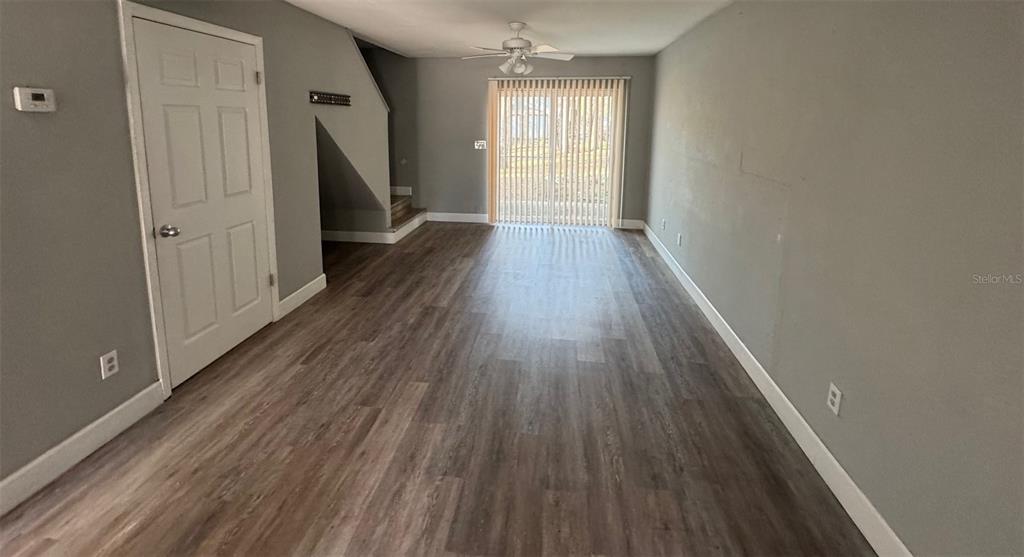 An empty room features gray walls, wood-look flooring, a ceiling fan, and sliding glass doors — 7130 SW 45TH PLACE UNIT B, GAINESVILLE, FL