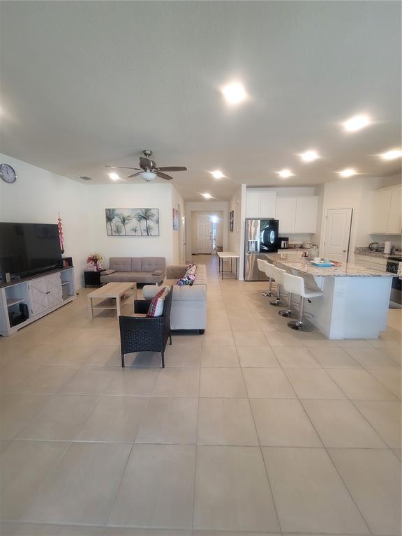 An open-concept living room and kitchen featuring tile flooring, a kitchen island, and recessed lighting — 7238 STEER BLADE DRIVE, ZEPHYRHILLS, FL