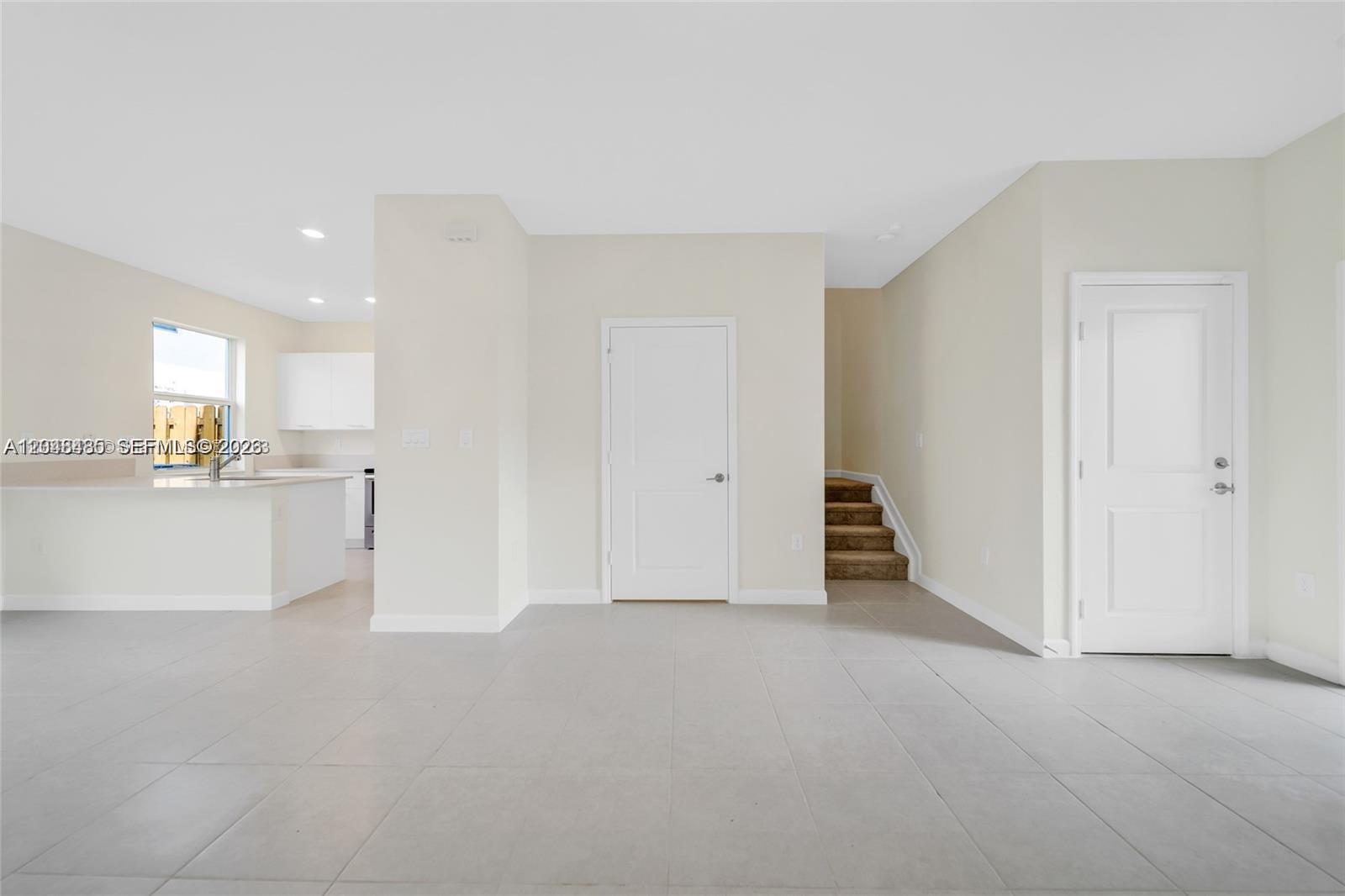 An interior view shows a tiled living area with a kitchen, stairs, and two doors — 12918 NW 23rd Pl, Miami FL 33167, MIAMI, FL