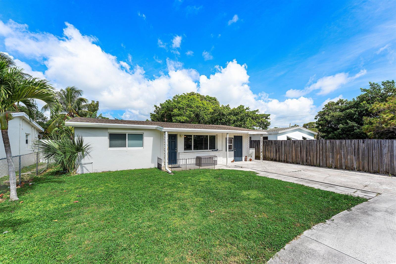 A single-story house with a white exterior, two dark doors, and a concrete driveway — 707 S Broadway, Lantana FL 33462, LANTANA, FL
