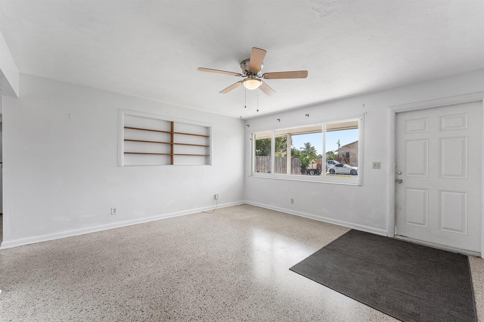 A bright living room features white walls, a ceiling fan, and speckled terrazzo flooring — 707 S Broadway, Lantana FL 33462, LANTANA, FL