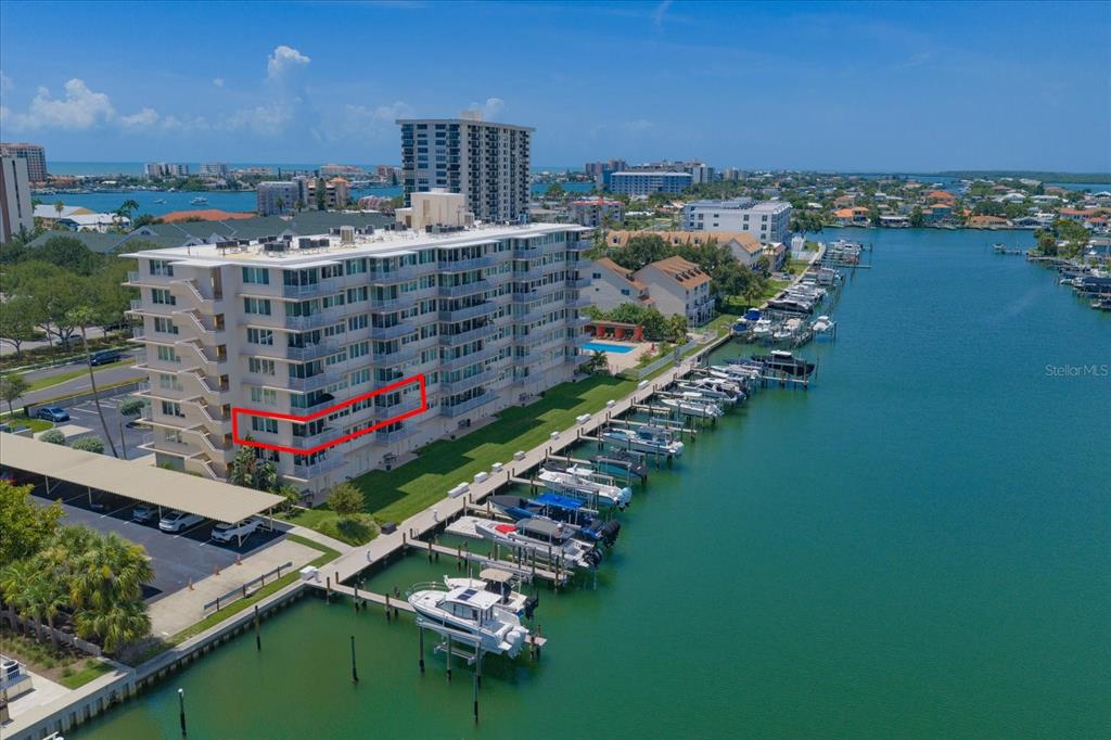 An aerial view shows a multi-story waterfront condominium building with a red-outlined unit balcony — 223 ISLAND WAY UNIT 2E, CLEARWATER BEACH, FL