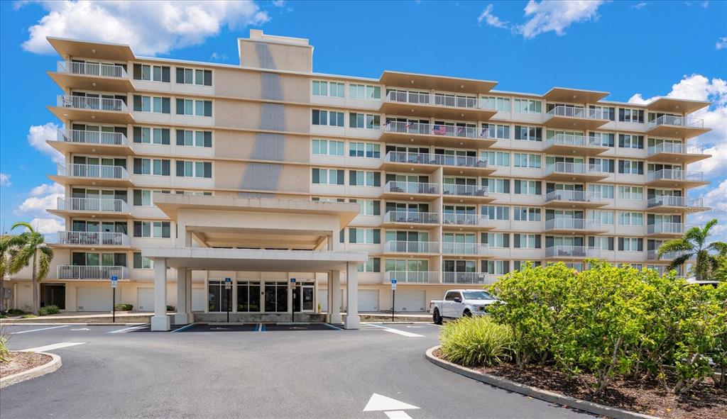 A multi-story apartment building with a covered entrance and a parking lot in front — 223 ISLAND WAY UNIT 2E, CLEARWATER BEACH, FL