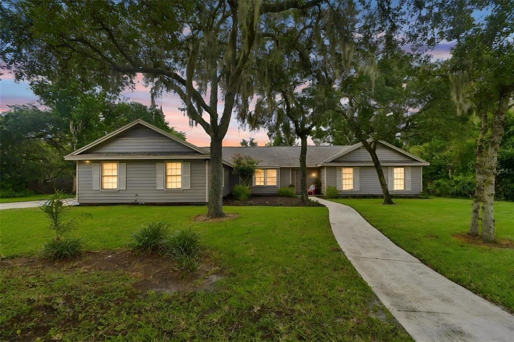 A single-story gray house with a concrete walkway and large oak trees in the yard — 755 KEENELAND PIKE, LAKE MARY, FL