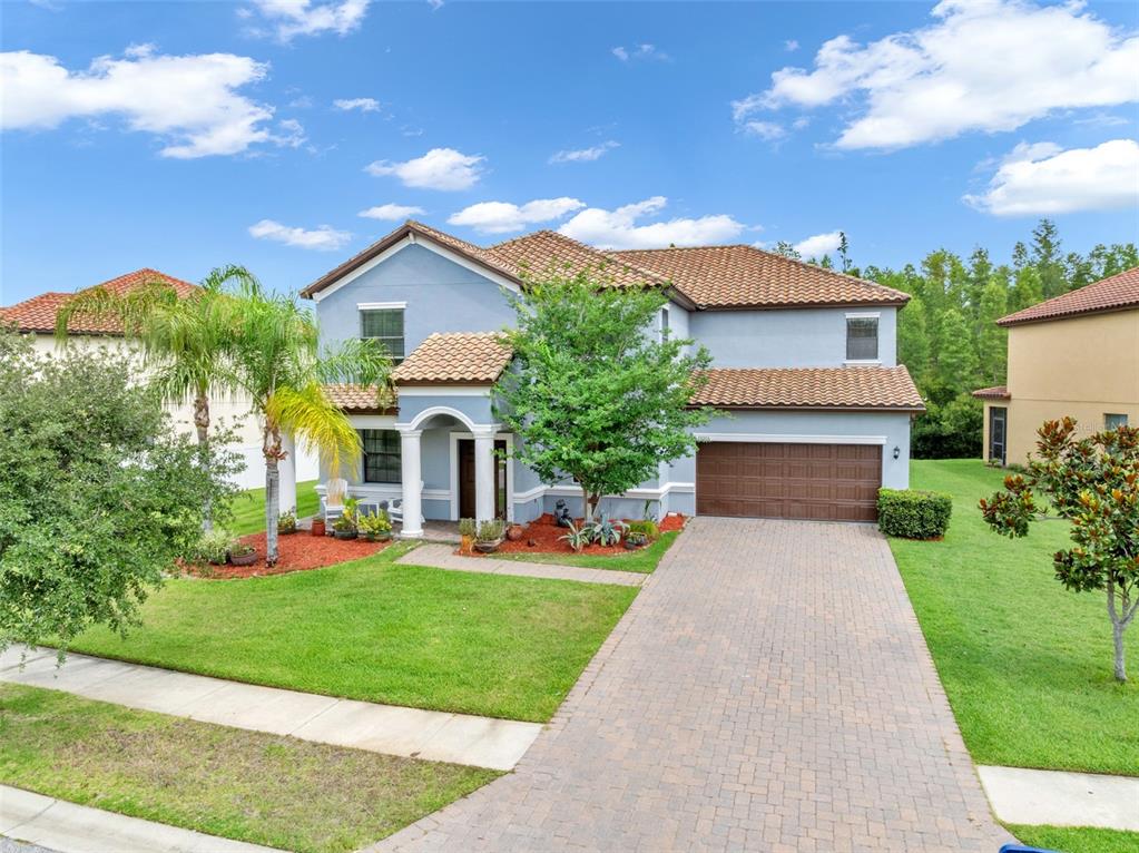 A two-story blue house with a tile roof, a brick driveway, and a front lawn — 19265 UMBERLAND PLACE, LAND O LAKES, FL