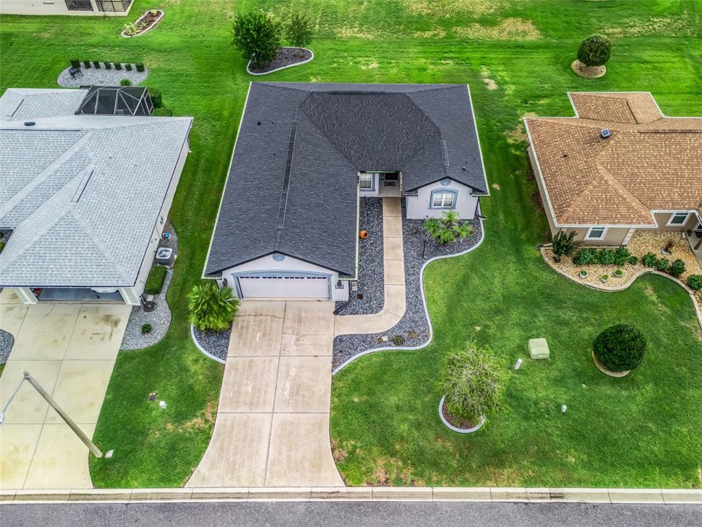 An aerial view shows a single-story house with a dark roof, garage, and concrete driveway — 12115 SE 176TH LOOP, SUMMERFIELD, FL