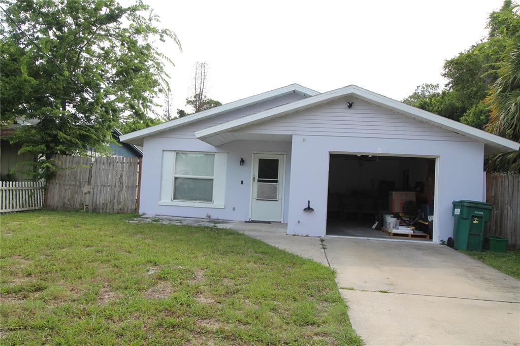 A light purple single-story house features a front-facing garage and a small concrete driveway — 812 OLEANDER AVENUE, HOLLY HILL, FL