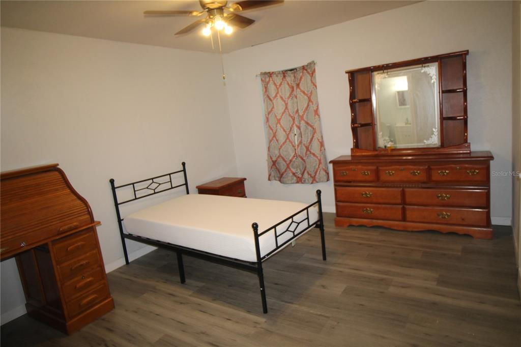 A bedroom features a metal bed frame, wooden dresser with mirror, and a roll-top desk — 812 OLEANDER AVENUE, HOLLY HILL, FL