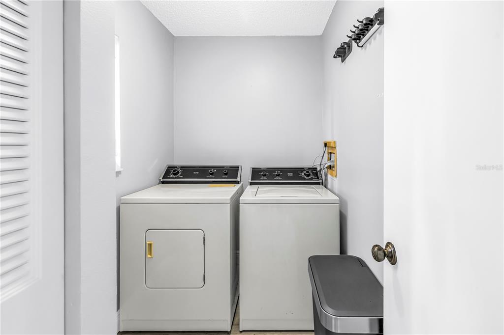 A laundry room features a white washer and dryer set against a plain wall — 723 83RD AVENUE N UNIT 102, ST PETERSBURG, FL