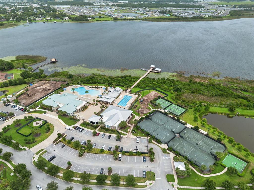 Aerial view of a community clubhouse complex featuring swimming pools, tennis courts, and a dock — 2777 SOUTHLAND STREET, ST CLOUD, FL
