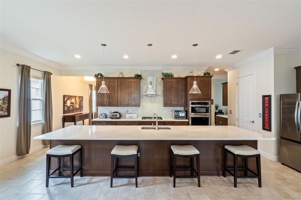 A kitchen features a large white island with four stools and dark wood cabinetry — 2777 SOUTHLAND STREET, ST CLOUD, FL
