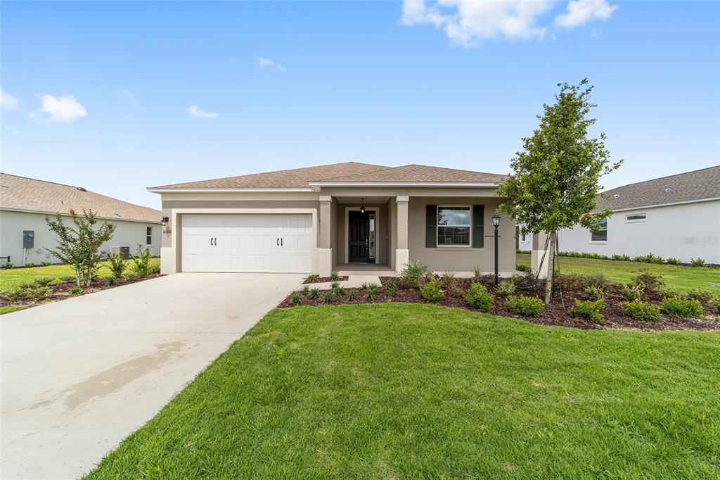 A single-story suburban house with a two-car garage, tan stucco exterior, and landscaped front yard — 10352 SW 107TH COURT, OCALA, FL