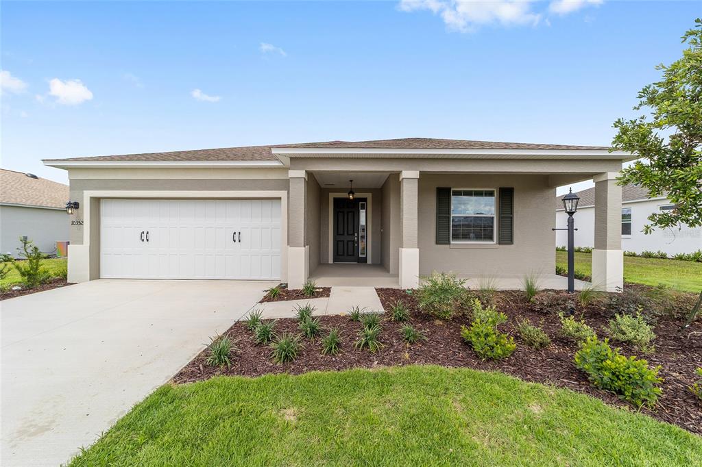 A single-story house with a two-car garage, covered entryway, and landscaped front yard — 10352 SW 107TH COURT, OCALA, FL