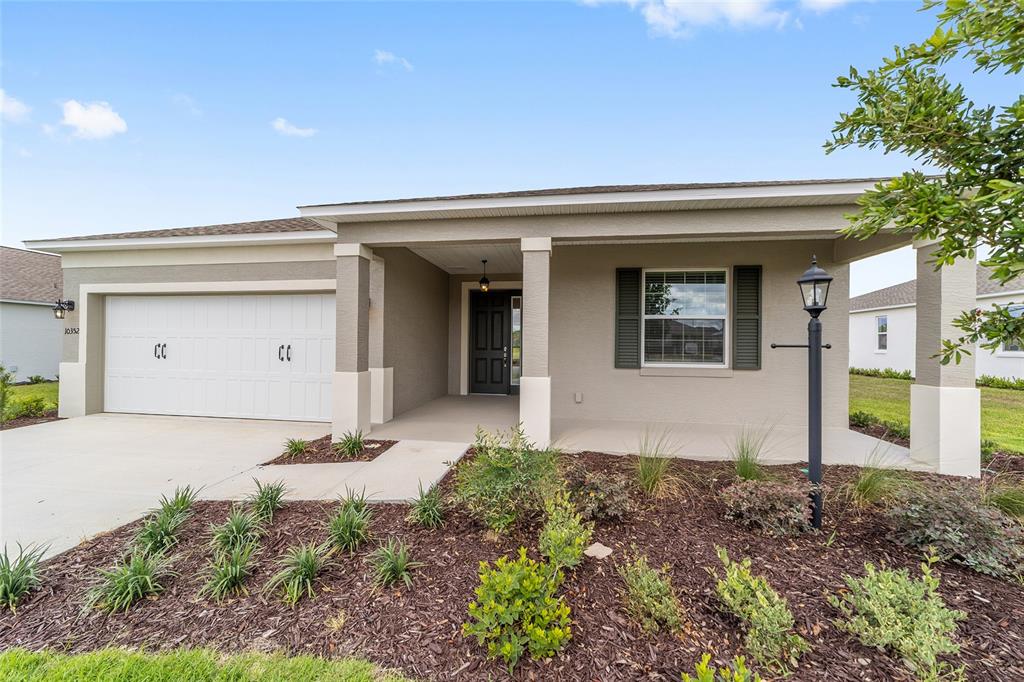 A single-story house with a two-car garage, covered entryway, and landscaped front yard — 10352 SW 107TH COURT, OCALA, FL