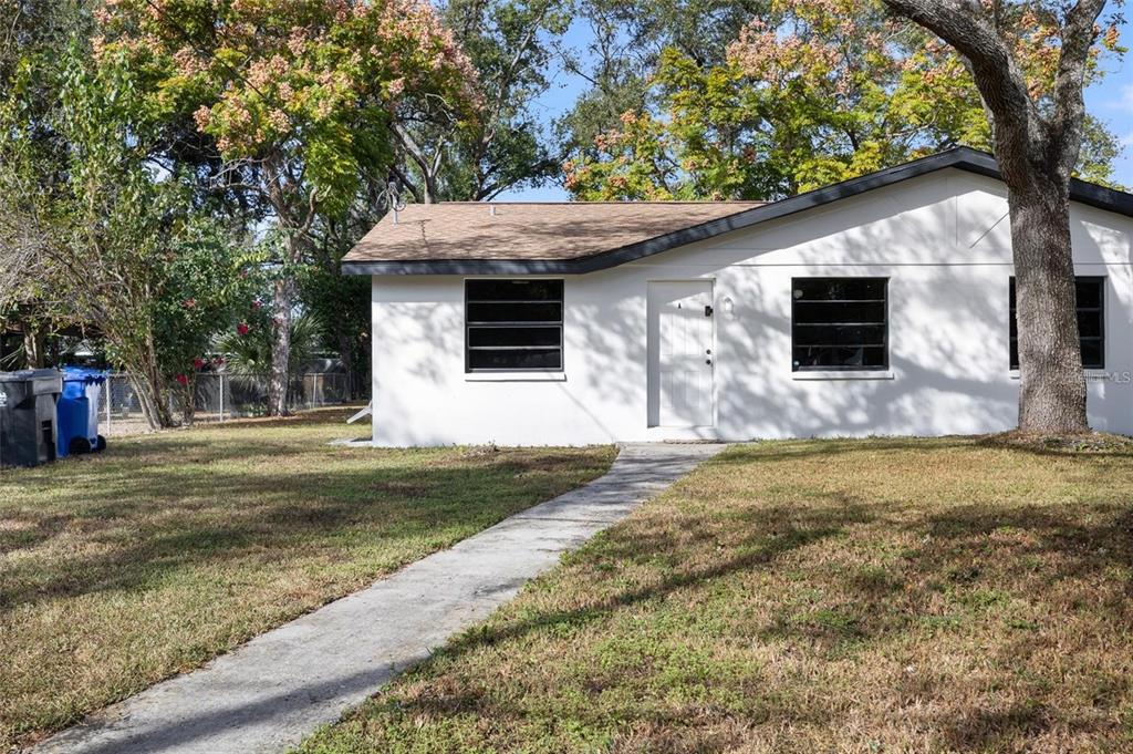 A white, single-story house with a brown roof and a concrete walkway in the yard — 1220 E 142ND AVENUE UNIT A, TAMPA, FL