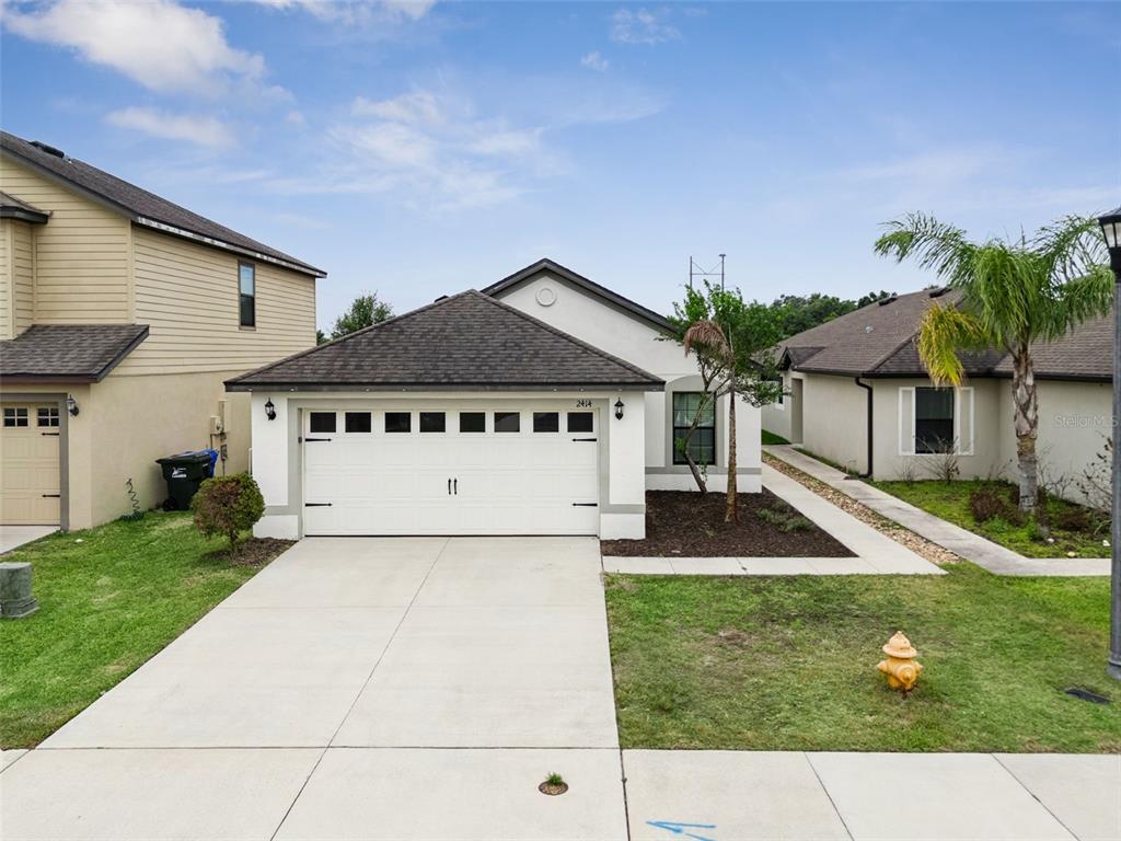A single-story house with a white garage, tan siding, and a concrete driveway — 2414 CASPIAN DRIVE, LAKELAND, FL