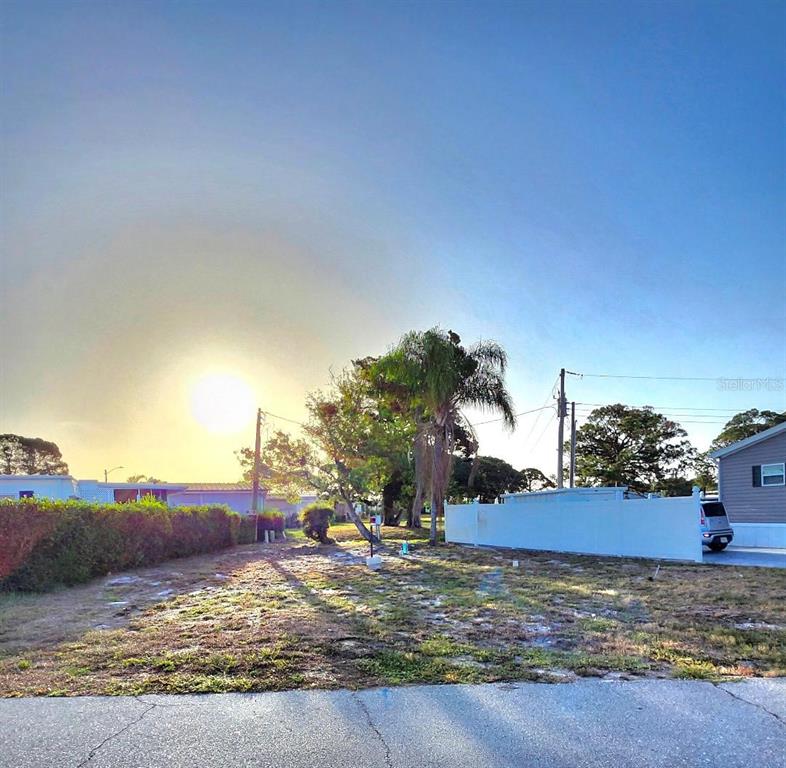 A vacant, grassy residential lot features a palm tree and a white privacy fence — 6509 NEW JERSEY STREET, BRADENTON, FL