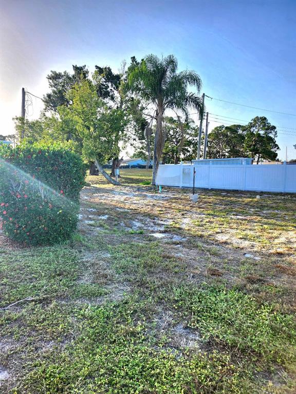 A vacant, grassy lot features a palm tree, a white vinyl fence, and a flowering bush — 6509 NEW JERSEY STREET, BRADENTON, FL
