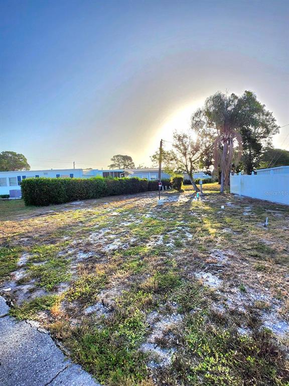 A vacant, grassy lot with a palm tree and a white fence in a neighborhood — 6509 NEW JERSEY STREET, BRADENTON, FL