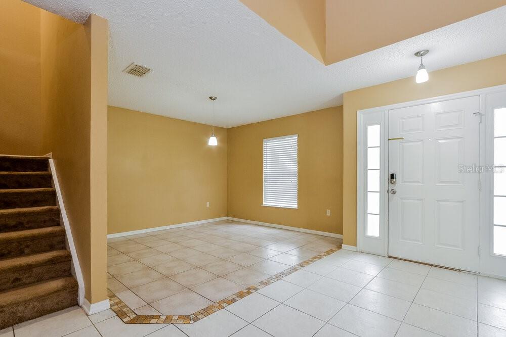 An entryway with tiled floors, a staircase, and a dining area with a pendant light — 2047 GALAHAD DRIVE, DELTONA, FL