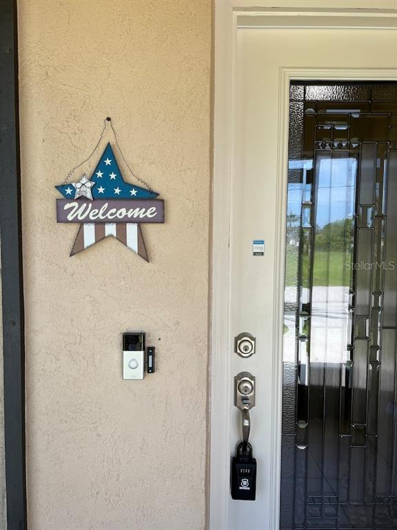 A front door with a decorative star sign and a smart doorbell on the wall — 87 MARK TWAIN LANE, ROTONDA WEST, FL