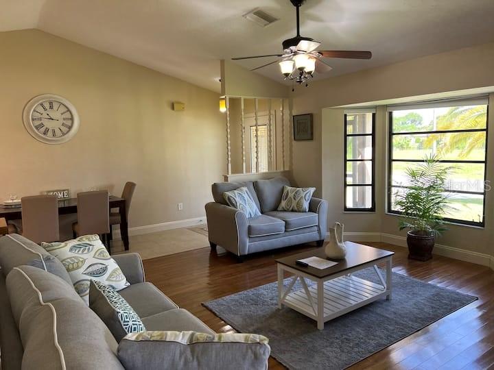 A living room features hardwood floors, a ceiling fan, a sofa, and a dining area — 87 MARK TWAIN LANE, ROTONDA WEST, FL