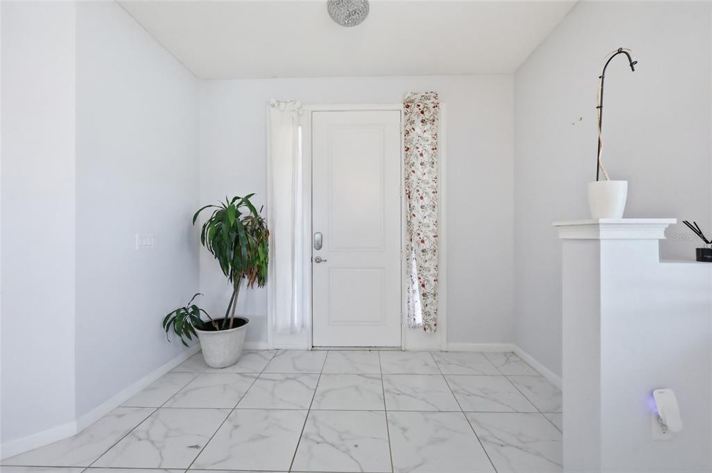 A bright entryway features white marble-look tile flooring, a white front door, and a potted plant — 2252 RUSH BAY WAY, ORLANDO, FL