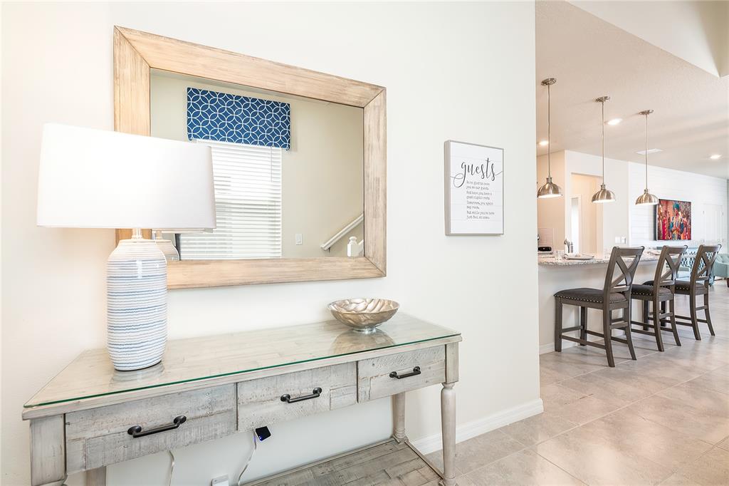 A wooden console table with a lamp and mirror sits in a bright entryway — 3783 LANA AVENUE, DAVENPORT, FL