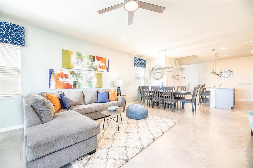 An open-concept living and dining area features a gray sectional sofa, dining table, and tile flooring — 3783 LANA AVENUE, DAVENPORT, FL
