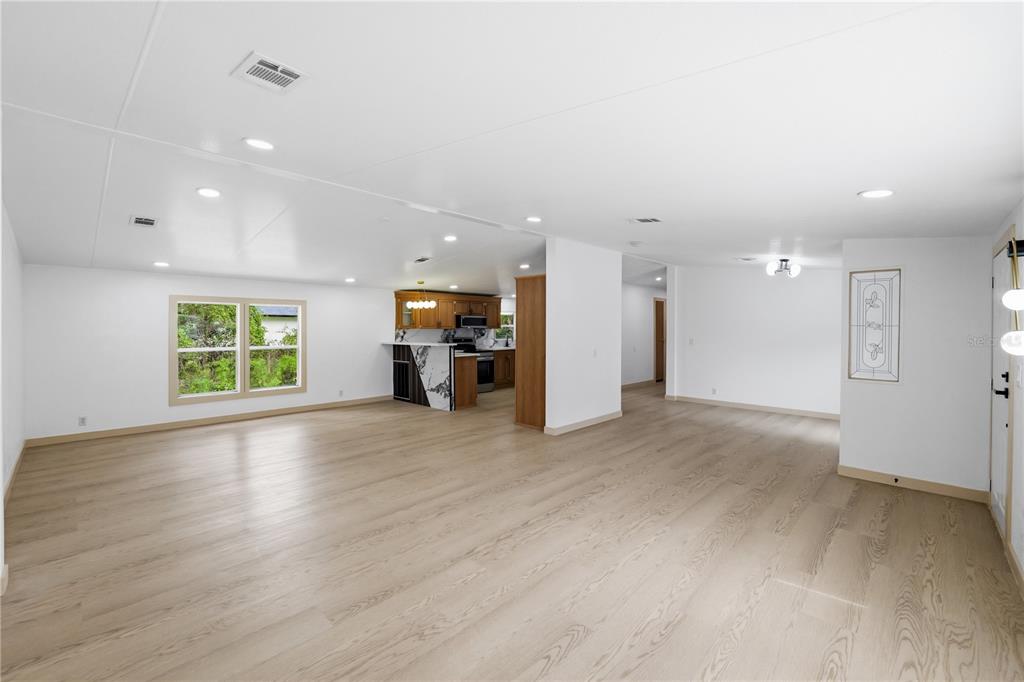 An open-concept living area features light wood-look flooring, white walls, and a kitchen with wood cabinets — 8726 N MEADOWVIEW CIR, TAMPA, FL