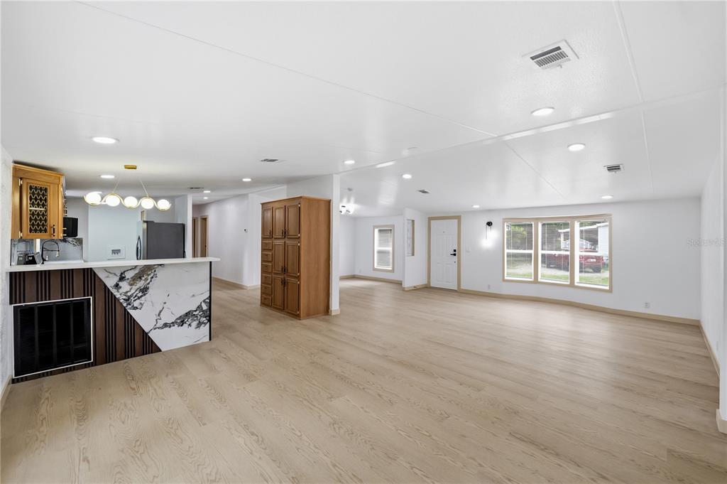 An open-concept living area features light wood flooring, a marble-topped fireplace, and a tall wooden cabinet — 8726 N MEADOWVIEW CIR, TAMPA, FL