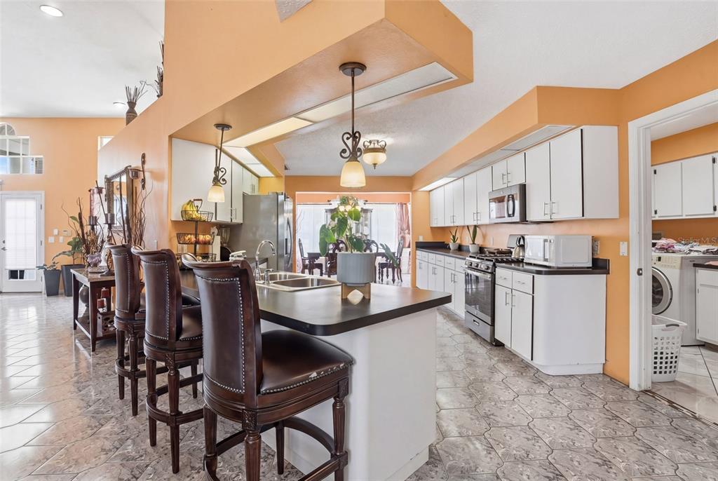 A kitchen with white cabinets, dark countertops, and a breakfast bar with leather stools — 23494 WESTCHESTER BOULEVARD, PUNTA GORDA, FL