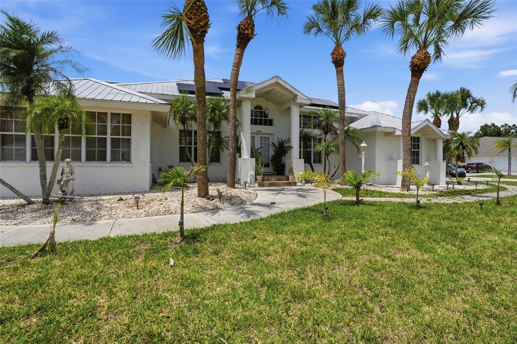 A single-story white house with a metal roof and palm trees in the front yard — 23494 WESTCHESTER BOULEVARD, PUNTA GORDA, FL