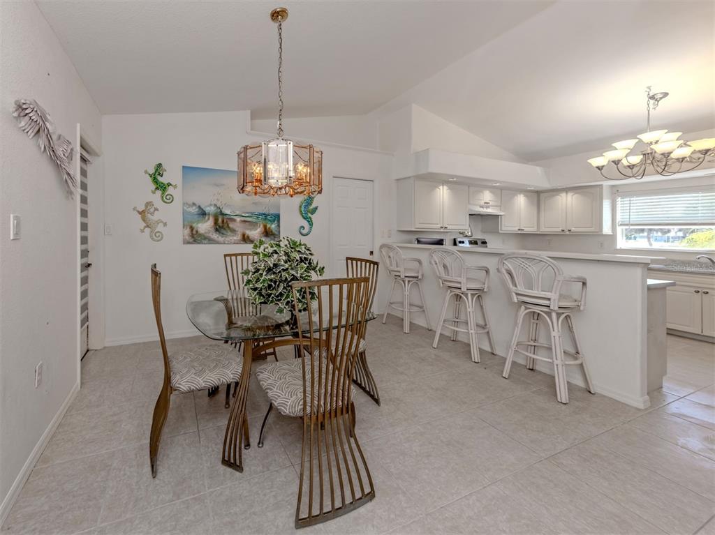 A dining area with a glass table and chairs sits adjacent to a kitchen counter — 1056 ROTONDA CIRCLE, ROTONDA WEST, FL