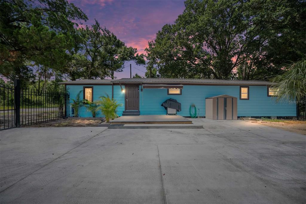 A single-story blue house with a concrete driveway and a small wooden deck entrance — 416 SW 5TH STREET, CHIEFLAND, FL