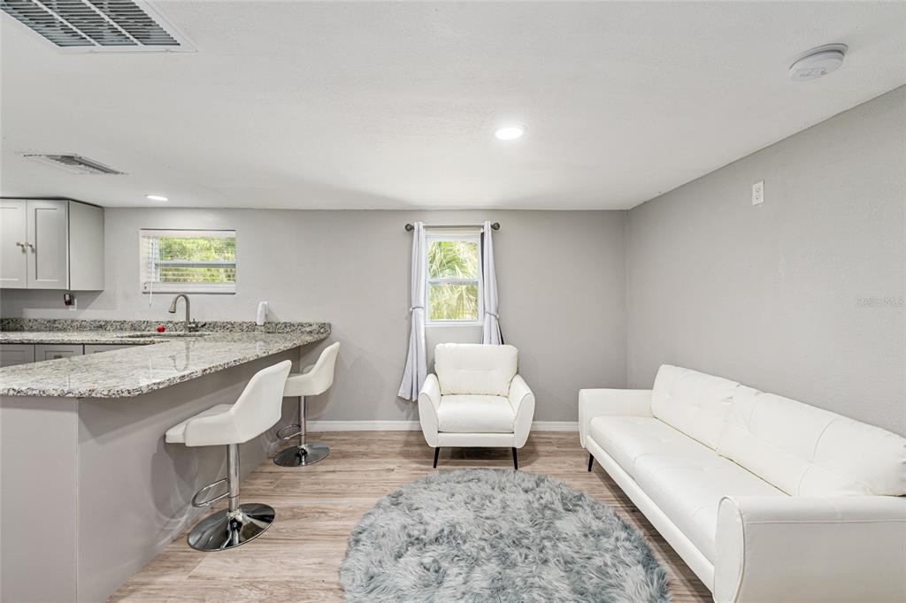 A kitchen with a granite breakfast bar and stools opens into a living area — 416 SW 5TH STREET, CHIEFLAND, FL