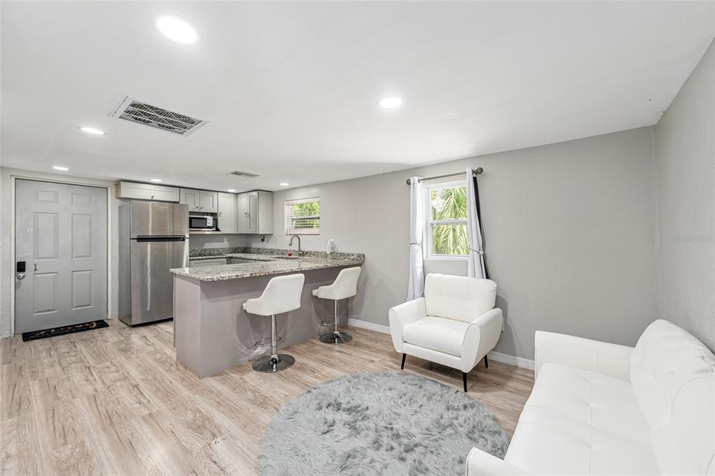 A small open-concept kitchen and living area with light wood floors and white furniture — 416 SW 5TH STREET, CHIEFLAND, FL