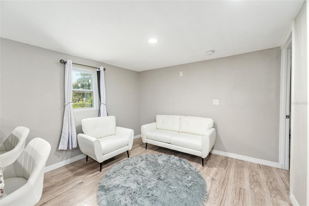 A living room features light gray walls, wood-look flooring, a white sofa, and an armchair — 416 SW 5TH STREET, CHIEFLAND, FL