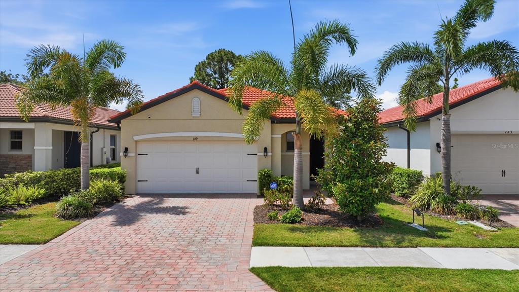 A single-story house with a red tile roof, beige stucco walls, and a brick driveway — 149 SOLIERA STREET, NOKOMIS, FL