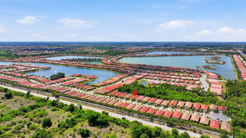 An aerial view shows a residential community with red-roofed houses surrounding a large lake — 149 SOLIERA STREET, NOKOMIS, FL