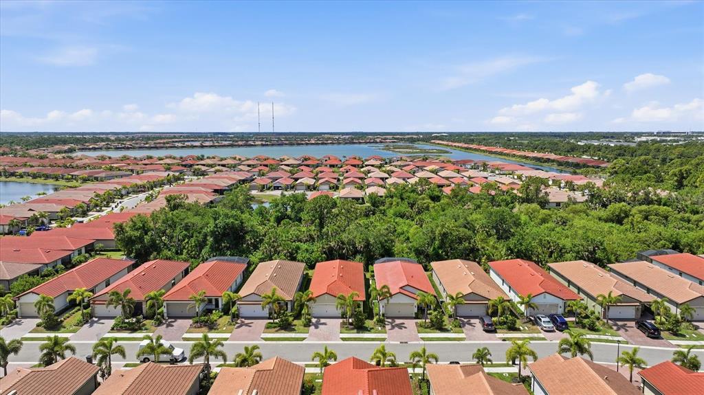 An aerial view shows a suburban neighborhood with rows of houses and a large lake — 149 SOLIERA STREET, NOKOMIS, FL