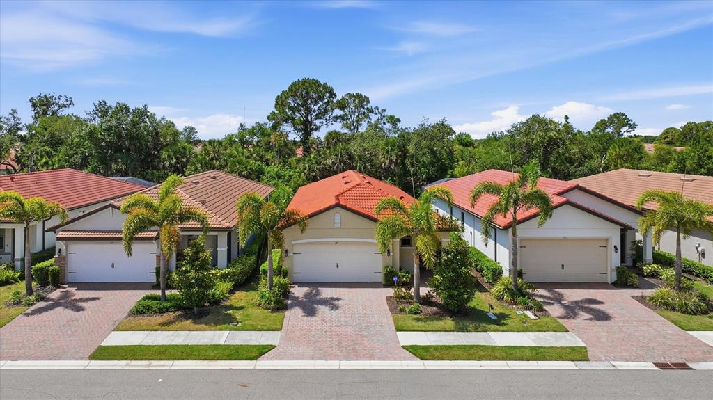 An exterior view of three suburban houses with tiled roofs and paved driveways — 149 SOLIERA STREET, NOKOMIS, FL