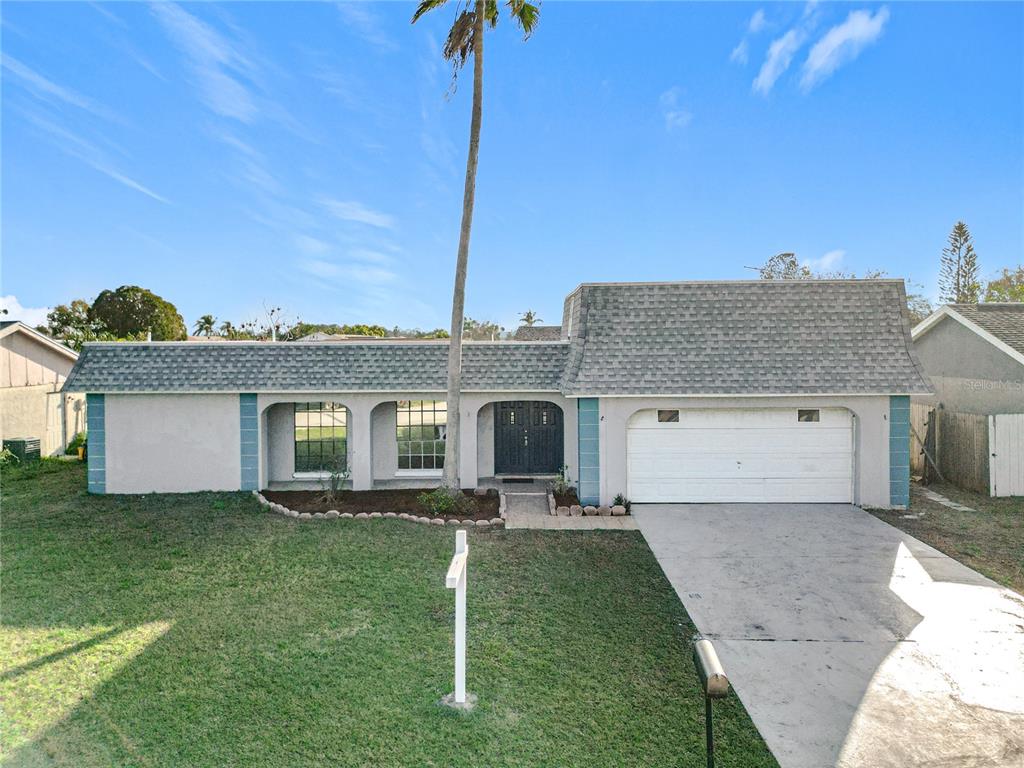 A single-story house with a gray shingled roof, a two-car garage, and a palm tree — 3640 RICHBORO DRIVE, HOLIDAY, FL