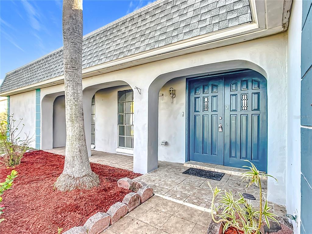 A blue double front door sits under a covered porch with arched concrete columns — 3640 RICHBORO DRIVE, HOLIDAY, FL